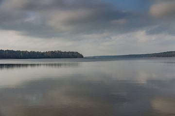 Fototapeta premium A calm blue lake with a wobbly cloud in the sky