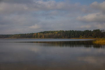 Tranquil lake with clouds in the sky and trees in autumn colors