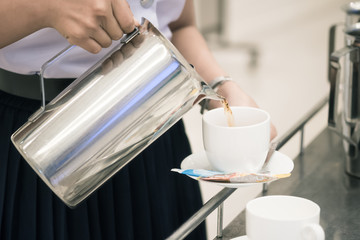 woman staff is pouring coffee in pot to serve guests attending seminar during break time in meeting room.