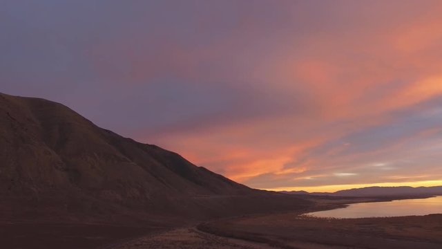 Aerial view of mountain side during colorful sunset along the edge of Utah Lake.
