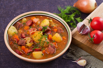 Stew, made with beef, bacon, sausages potatoes, carrots and herbs. Goulash soup bograch in a bowl. Hungarian dish