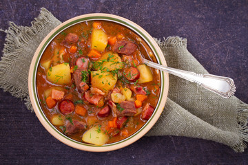 Stew, made with beef, bacon, sausages potatoes, carrots and herbs. Goulash soup bograch in a bowl....