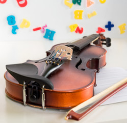  A Small Children's Violin and Bow on a Child's Study Desk - 182603389