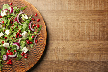 Wooden board with fresh tasty salad on table