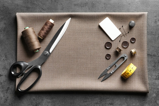 Set of tailoring tools, accessories and fabric on table, top view