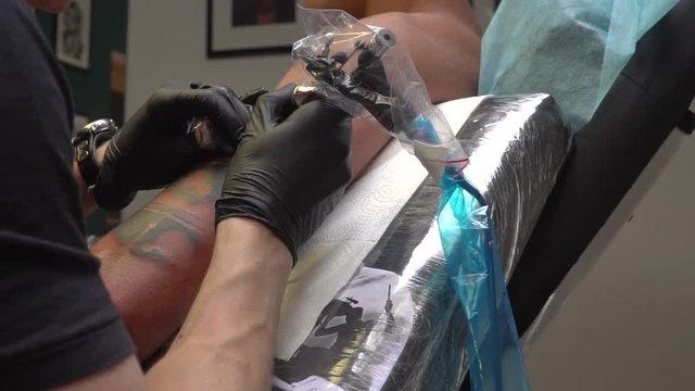 Tattoo artist makes a tattoo on a clients shoulder
