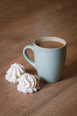 A cup of coffee with a biscuit in white chocolate on a wooden background
