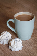 A cup of coffee with a biscuit in white chocolate on a wooden background