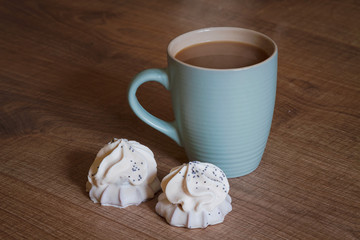 A cup of coffee with a biscuit in white chocolate on a wooden background