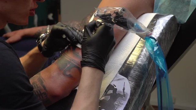 Professional tattoo artist makes a tattoo with a picture of a drummer on mans hand