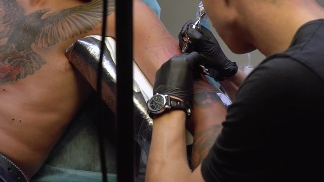 Guy with a tattoo came to the tattoo artist to make another