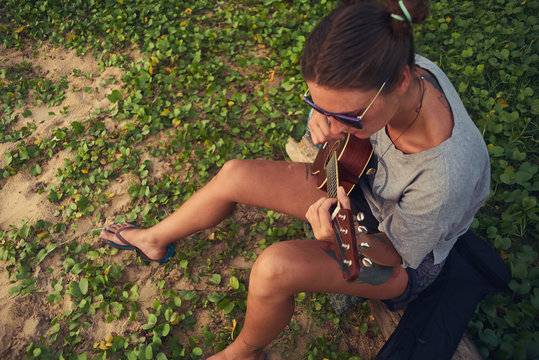 young female playing ukulele on a tropical beach