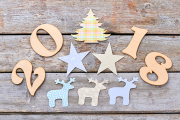 New Year 2018 wooden background. Cut out wooden number 2018, paper figures of Christmas tree, deers and stars on wooden rustic background. Winter handmade craft. Happy New Year 2018.