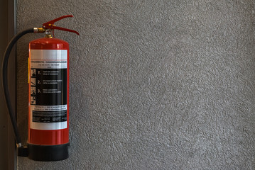 Red fire extinguisher hanging on the wall inside a shopping complex in the city of Lappeenranta,...