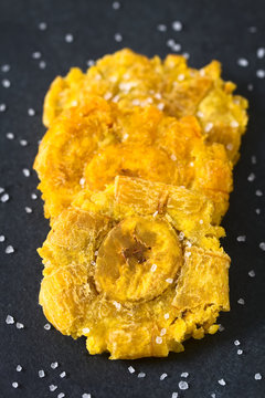 Salted patacon or toston, fried and flattened pieces of green plantains, a traditional snack or accompaniment in the Caribbean, photographed on slate with natural light