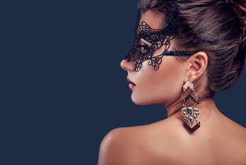 Beautiful brunette model wearing lace carnival mask and jewellery. New year party.