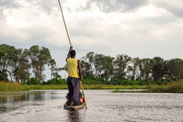 Canoe trip with traditional mokoro boat on the river through Okavango Delta near Maun, Botswana...