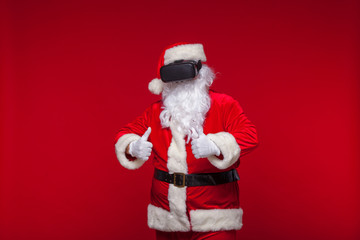 Santa Claus wearing virtual reality goggles, on a red background. Christmas