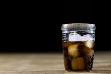 Soda and bottle on a wooden table. A glass and a bottle of beverage on the table.