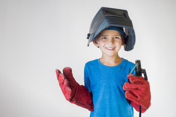 Happy little kid in welder mask and welding equipment. - obrazy, fototapety, plakaty