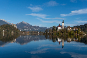 Fototapeta na wymiar The famous lake bled island and church in the foreground with the castle and the alps in the backdrop
