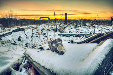 The post-apocalyptic world.Nuclear winter.Old gas mask in the ruins. The remains of houses covered with snow at sunset