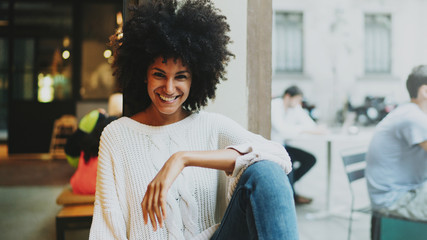 Half length portrait of a cheerful female with afro hair style wearing stylish clothes smiling at...