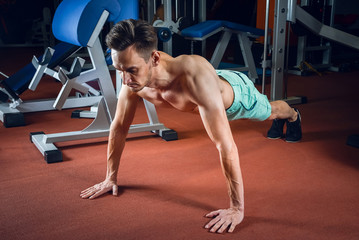Fototapeta na wymiar Handsome caucasian man working out and doing push ups at gym. Bodybuilding, sport and fitness lifestyle.
