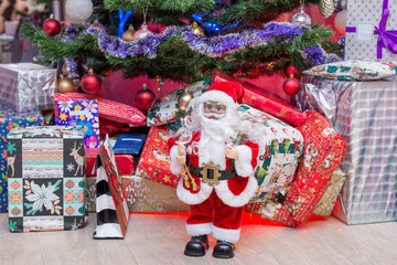 Decorated Christmas tree, gifts and Santa Claus.
