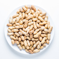 Raw peanuts in a plate on white background