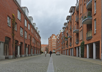 View down a cobblestone street with terraced houses with red brick walls on both sides