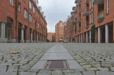 View down a cobblestone street with terraced houses with red brick walls on both sides