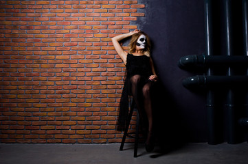 Halloween skull make up girl wear in black against brick wall at studio.