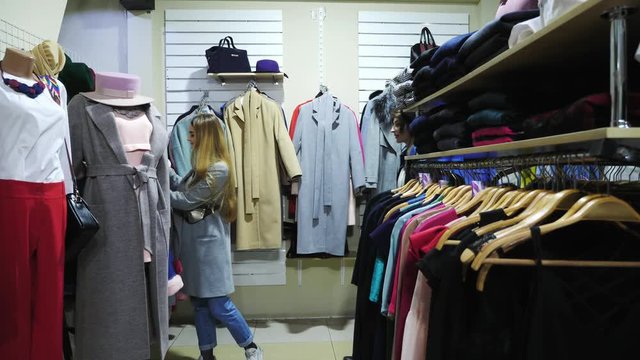 Two girls choose a coat in a store.