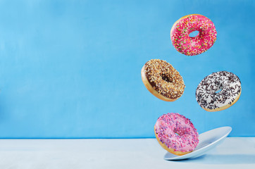 Flying multicolored donuts with plate - obrazy, fototapety, plakaty