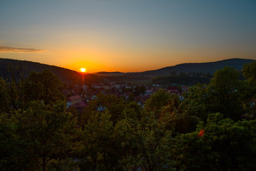 Beautiful landscape of sunrise over small town in forest mountains. Romania, Sighisoara - 2016.