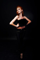 Fashion model red haired girl with originally make up like leopard predator isolated on black. Studio portrait.