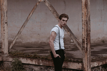 A handsome and stylish guy walks the old abandoned streets