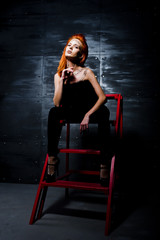 Obraz na płótnie Canvas Fashion model red haired girl with originally make up like leopard predator against steel wall. Studio portrait on ladder.