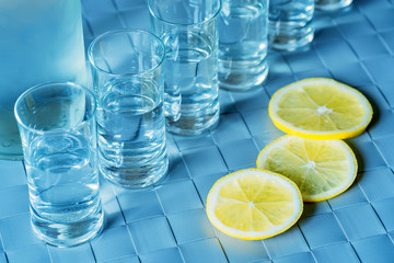 Vodka shot glass and lemon on blue surface