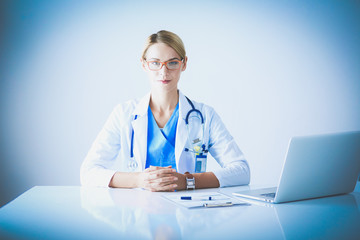 Beautiful young smiling female doctor sitting at the desk