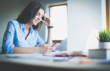 Beautiful young business woman sitting at office desk and talking on cell phone. Business woman