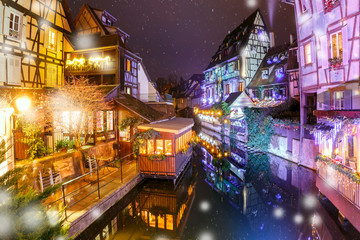 Traditional Alsatian half-timbered houses in Petite Venise or little Venice, old town of Colmar, decorated and illuminated at snowy christmas night, Alsace, France - obrazy, fototapety, plakaty