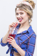 Youth Fashion and Lifestyle Concepts. Smiling Sexy caucasian Blond Girl Posing in Latex Pants against White.Drinking Juice Using Straw