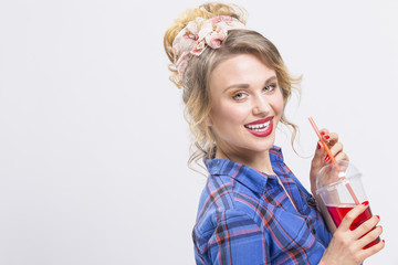 Youth Fashion and Lifestyle Concepts. Alluring and Happy Caucasian Blond Girl Posing in Checked Shirt and Headband Drinking Juice Using Straw.