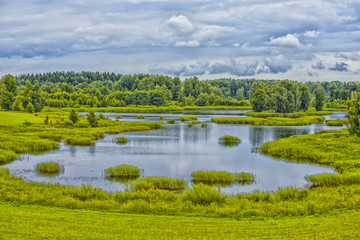 Fototapeta na wymiar Travel Concepts and Ideas. Belarussian National Park Braslav Lakes Surrounded by Densely Forested Area at Noon During Summertime.