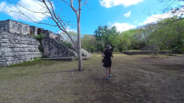 Gimbal shot of woman walking in mayan ruins at ek balam