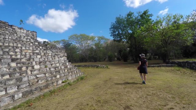 Gimbal shot of woman walking through mayan ruins at ek balam