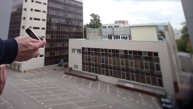 Open flip clamshell style cellphone in the hand with background of modern building. Footage. Retro flip flop Mobile Phone in hand close-up