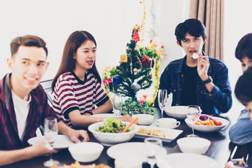 Dinner with Asian Group of best friends enjoying evening drinks while sitting at the dinning table on the kitchen together,soft focus